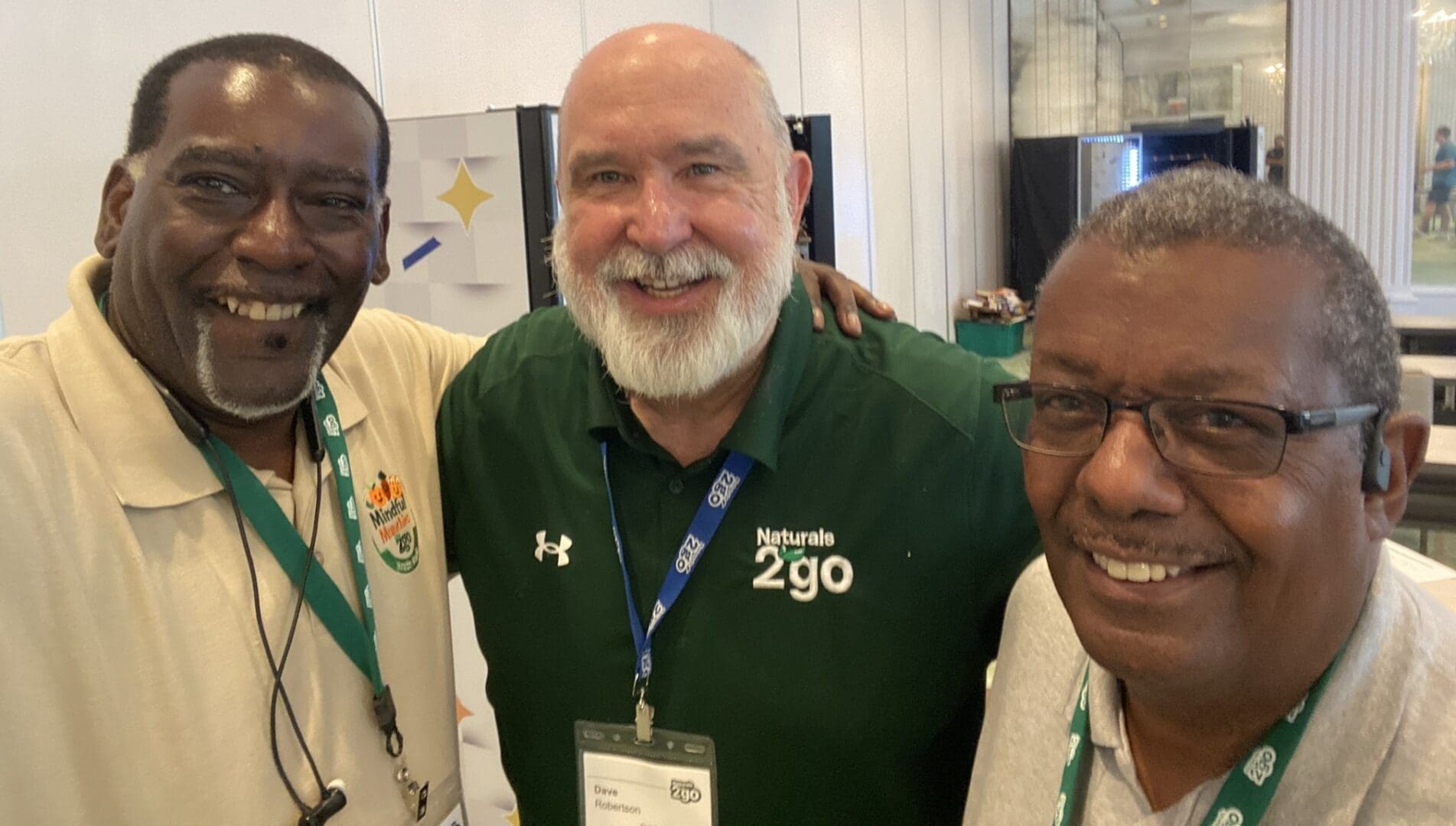 Three smiling men at a conference event.